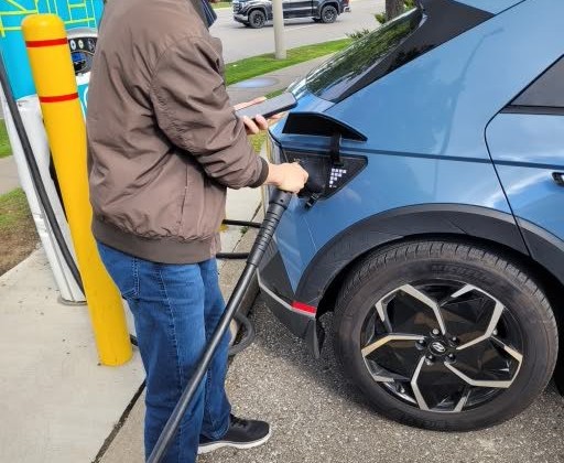 Person plugging an EV charging cable into a car — the hardware your platform certified